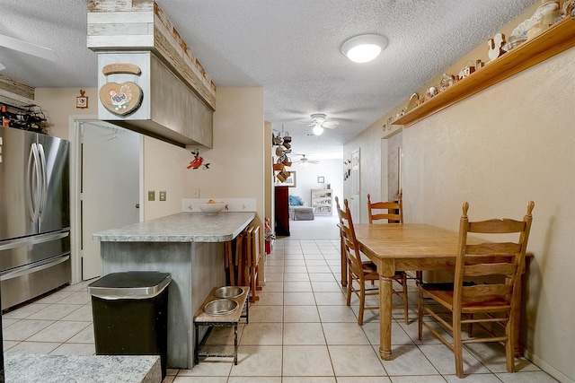 kitchen with a textured ceiling, stainless steel refrigerator, ceiling fan, and light tile patterned floors