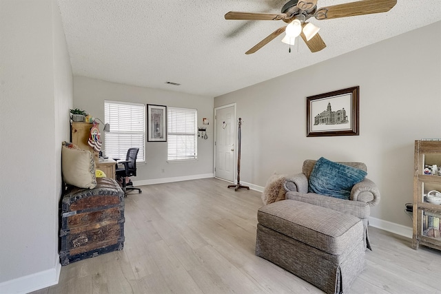 living area featuring ceiling fan, a textured ceiling, and light hardwood / wood-style flooring