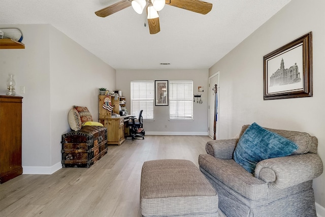 living area featuring ceiling fan, a textured ceiling, and light wood-type flooring