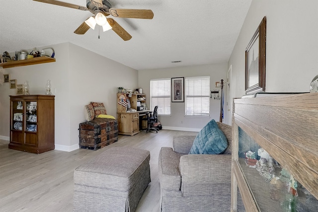 living room featuring ceiling fan, a textured ceiling, and light wood-type flooring