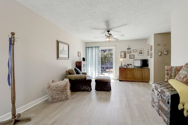 living area featuring ceiling fan, a textured ceiling, and light wood-type flooring