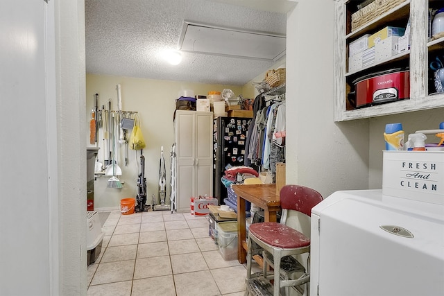 laundry room featuring a textured ceiling, washer / clothes dryer, and light tile patterned floors