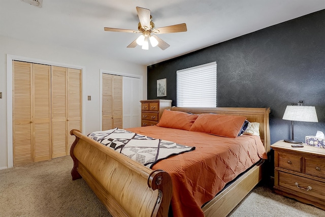 carpeted bedroom with two closets and ceiling fan