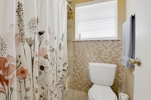 bathroom featuring tile walls, tile patterned floors, toilet, and curtained shower