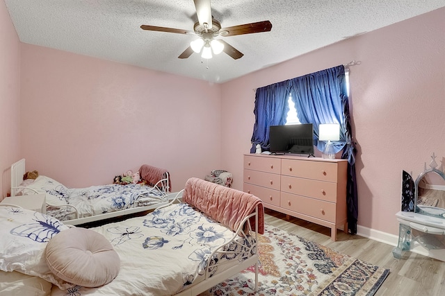 bedroom featuring light wood-type flooring, a textured ceiling, and ceiling fan