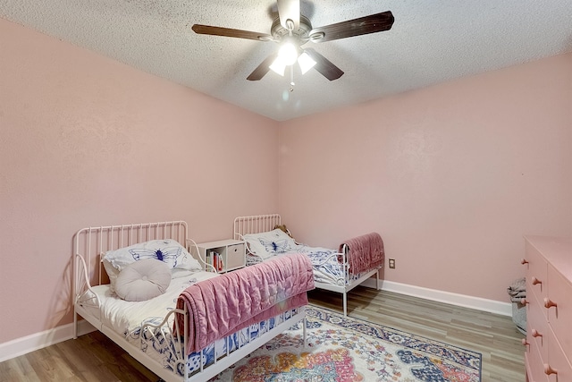 bedroom with a textured ceiling, hardwood / wood-style floors, and ceiling fan