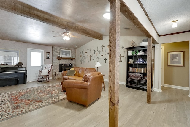 living room featuring ceiling fan, vaulted ceiling with beams, wood-type flooring, a brick fireplace, and a textured ceiling