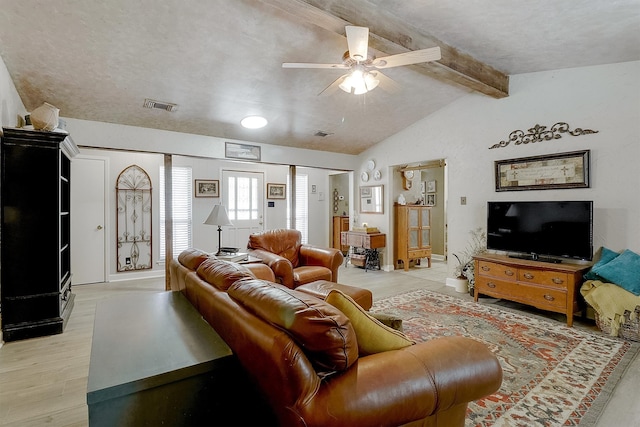 living room with ceiling fan, vaulted ceiling with beams, a textured ceiling, and light hardwood / wood-style flooring