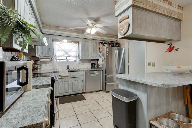 kitchen with a textured ceiling, light tile patterned floors, ceiling fan, and stainless steel appliances