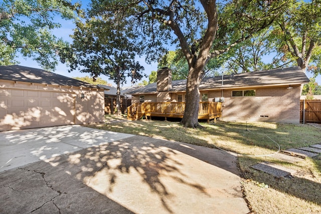 back of house with a garage, a deck, and a lawn