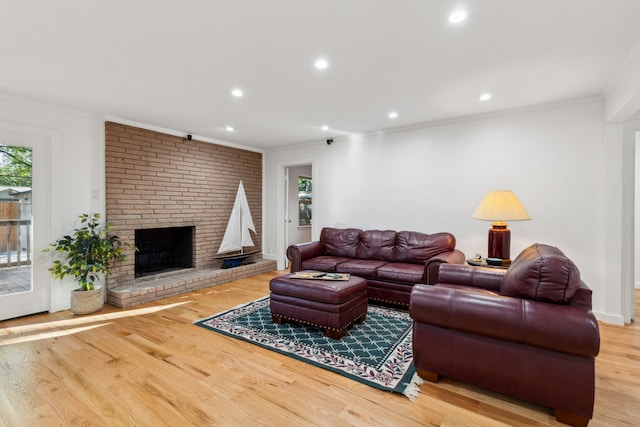 living room with crown molding, a fireplace, and light hardwood / wood-style flooring