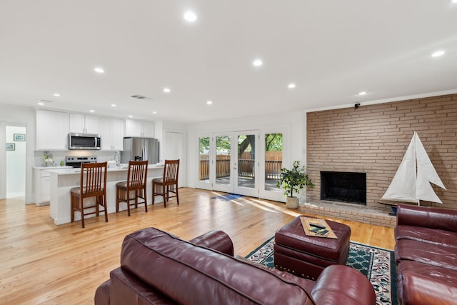 living room with light hardwood / wood-style flooring, french doors, a fireplace, and sink