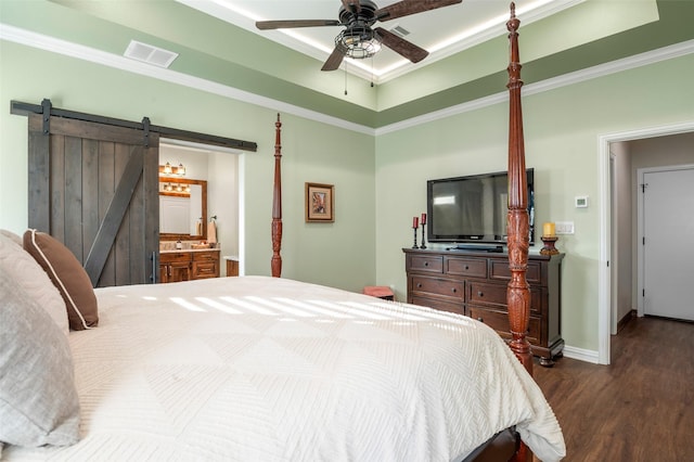 bedroom with ensuite bathroom, dark hardwood / wood-style floors, a barn door, ceiling fan, and ornamental molding