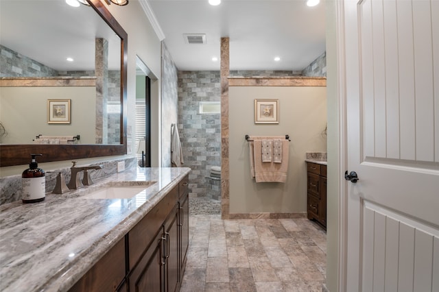 bathroom featuring a tile shower, vanity, and crown molding