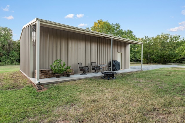 view of outdoor structure with a yard and a fire pit