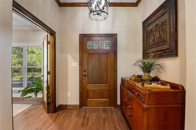 foyer featuring a notable chandelier, crown molding, and light hardwood / wood-style flooring