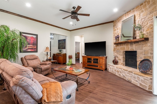 living room featuring a fireplace, dark hardwood / wood-style flooring, ceiling fan, and crown molding