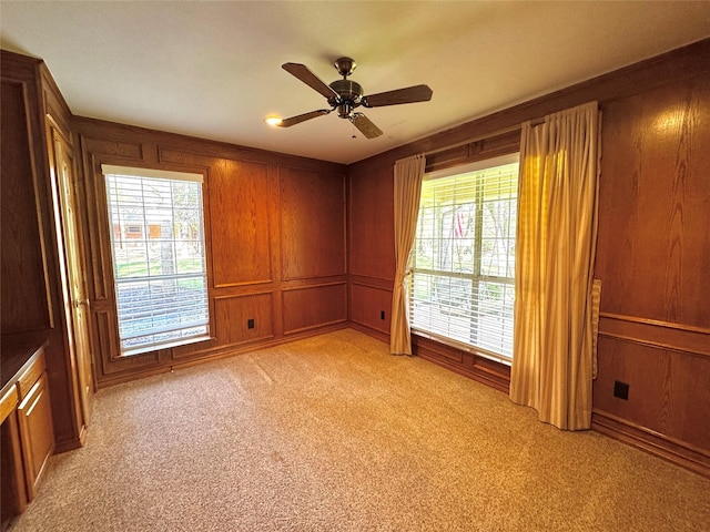 unfurnished room featuring ceiling fan, light colored carpet, and a decorative wall