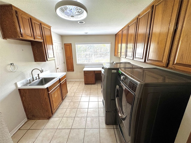 laundry area with a sink, washing machine and dryer, baseboards, cabinet space, and light tile patterned floors