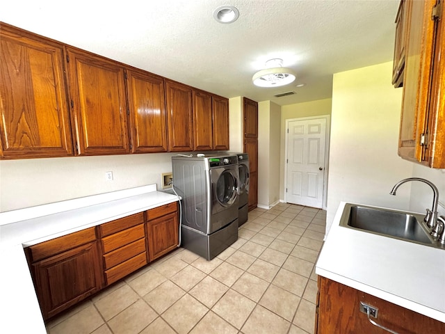 laundry room with a sink, light tile patterned flooring, visible vents, separate washer and dryer, and cabinet space