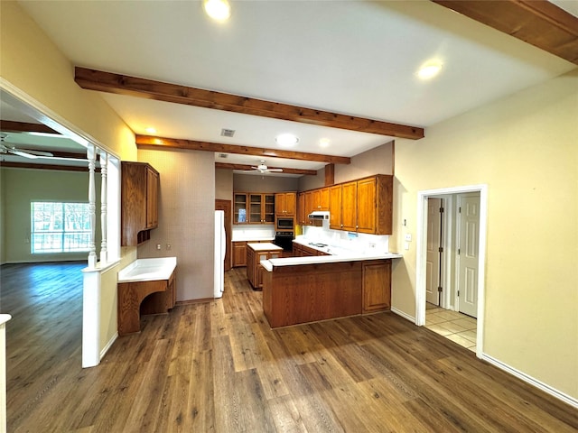 kitchen featuring a peninsula, freestanding refrigerator, wood finished floors, and ceiling fan