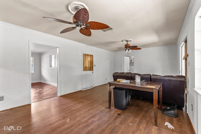 living room with ornamental molding, ceiling fan, brick wall, and dark wood-type flooring