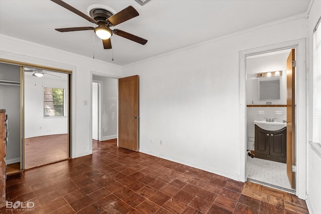 unfurnished bedroom with tile walls, a closet, ensuite bathroom, crown molding, and ceiling fan