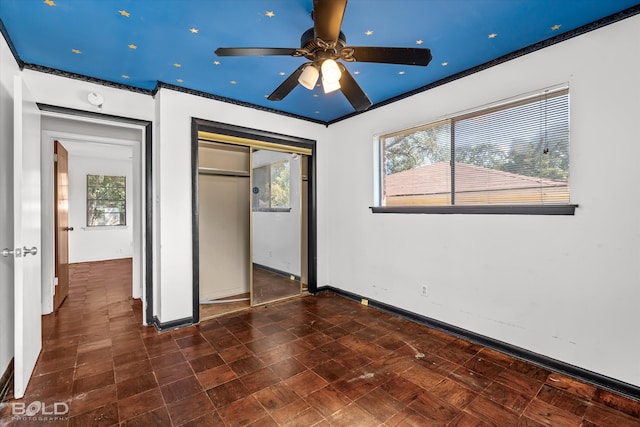 unfurnished bedroom with multiple windows, ceiling fan, and a closet