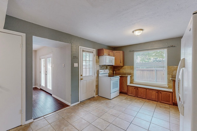 13818 Methuen Green Ln, Dallas, TX 75240 - kitchen with light tile patterned floors, light countertops, white appliances, and plenty of natural light