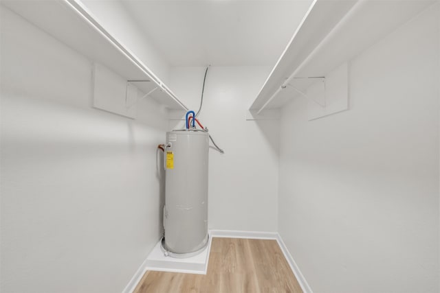 spacious closet with electric water heater and light hardwood / wood-style flooring