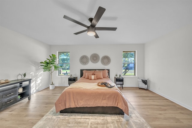 bedroom with light hardwood / wood-style floors, multiple windows, and ceiling fan