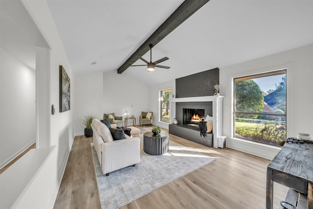 living room featuring a fireplace, lofted ceiling with beams, ceiling fan, and light hardwood / wood-style flooring