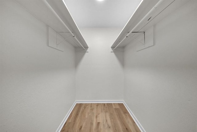 walk in closet with light hardwood / wood-style floors