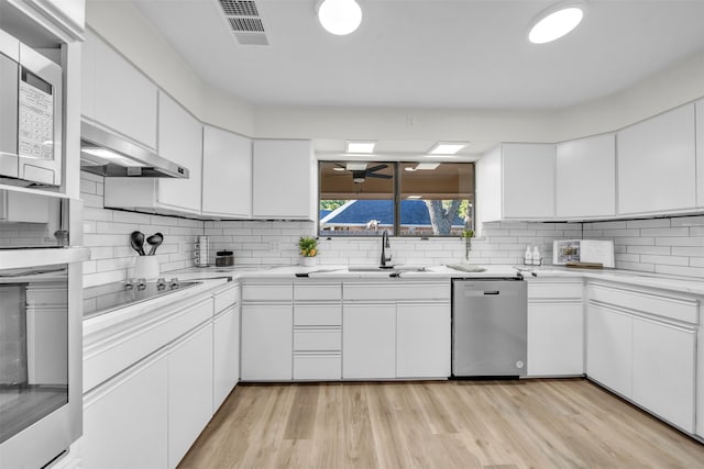 kitchen with white cabinets, sink, appliances with stainless steel finishes, light wood-type flooring, and decorative backsplash