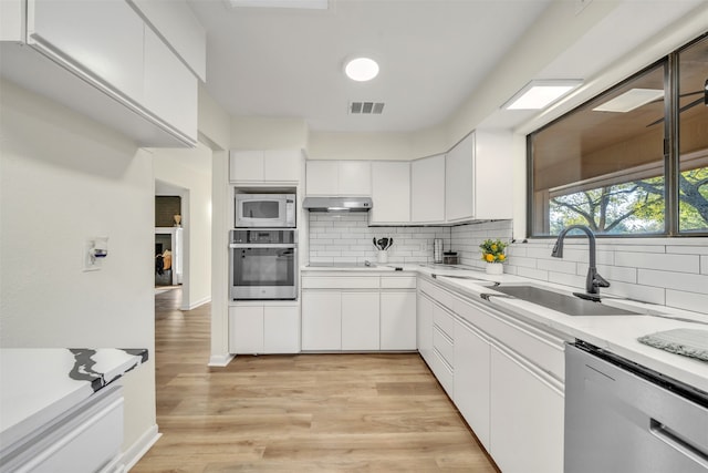 kitchen featuring decorative backsplash, white cabinetry, stainless steel appliances, light hardwood / wood-style flooring, and sink