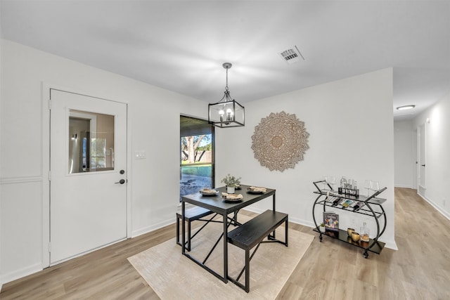 dining space with light hardwood / wood-style flooring and a notable chandelier