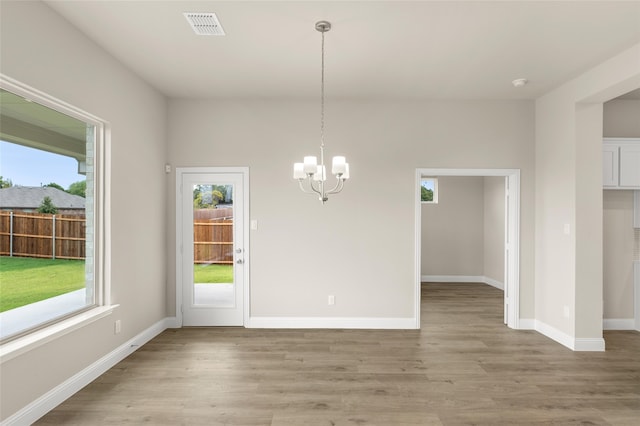 unfurnished dining area with light hardwood / wood-style floors and an inviting chandelier