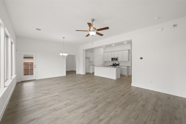 kitchen with appliances with stainless steel finishes, white cabinetry, and decorative light fixtures