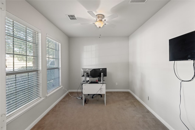 office featuring visible vents, light colored carpet, a ceiling fan, and baseboards