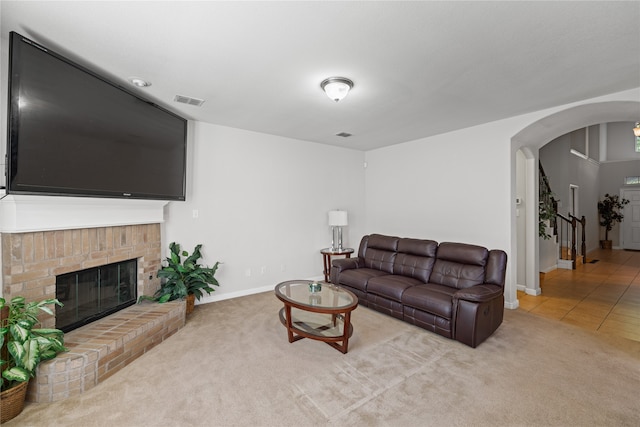 tiled living room featuring a fireplace, carpet flooring, visible vents, and arched walkways