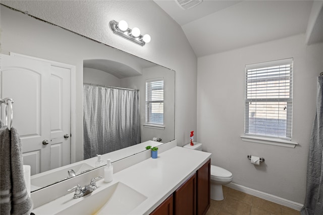 bathroom featuring vanity, baseboards, visible vents, lofted ceiling, and tile patterned flooring