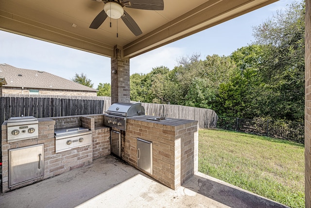 view of patio featuring grilling area, a ceiling fan, exterior kitchen, and a fenced backyard