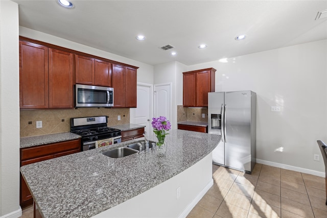 kitchen featuring visible vents, an island with sink, a sink, stainless steel appliances, and decorative backsplash