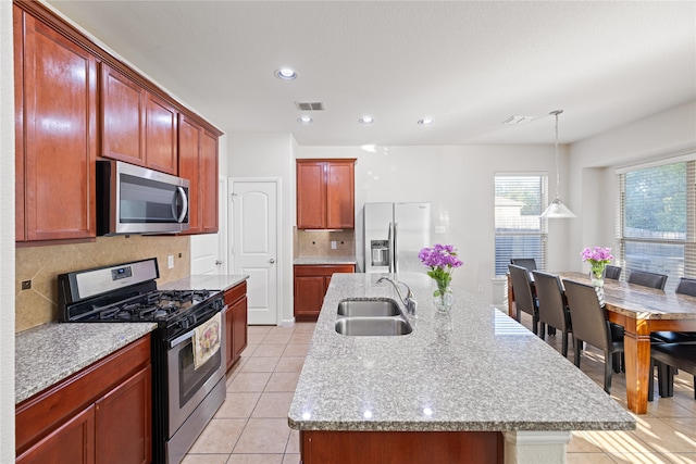 kitchen with tasteful backsplash, visible vents, a center island with sink, stainless steel appliances, and a sink