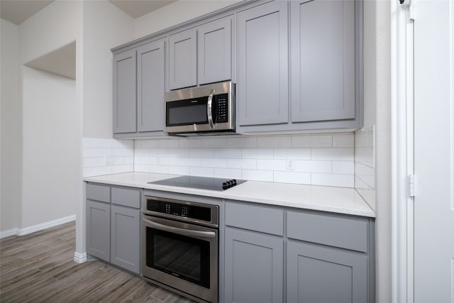 kitchen featuring gray cabinets, appliances with stainless steel finishes, tasteful backsplash, and light hardwood / wood-style flooring