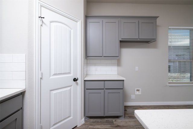 kitchen with gray cabinets, dark hardwood / wood-style floors, and decorative backsplash