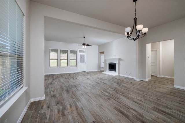 unfurnished living room featuring ceiling fan with notable chandelier and dark hardwood / wood-style flooring