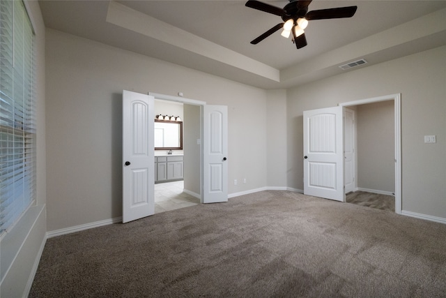 unfurnished bedroom featuring a tray ceiling, ceiling fan, light colored carpet, and sink