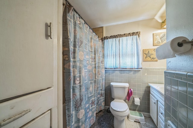full bath featuring a wainscoted wall, a shower with curtain, toilet, tile walls, and vanity