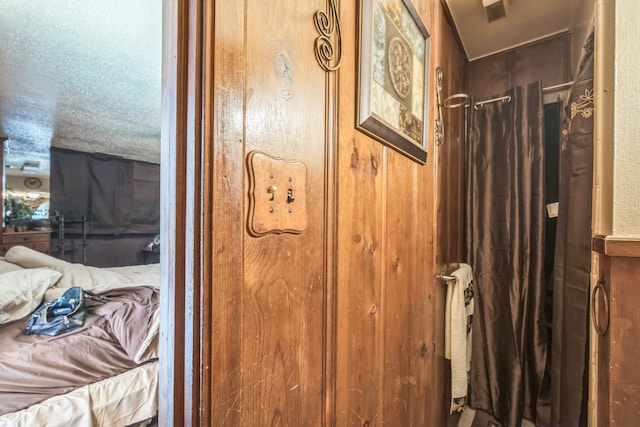 bathroom with a textured ceiling and wooden walls